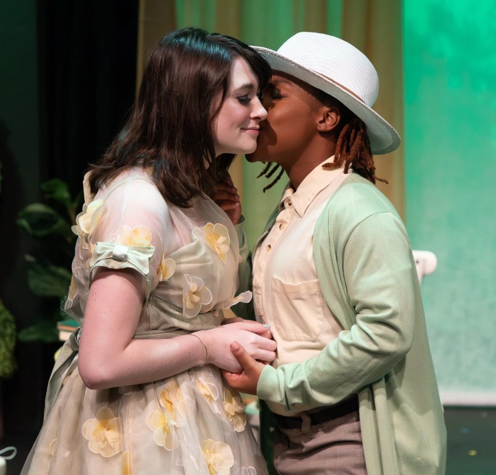 A fancy dressed couple kissing on cheek. 